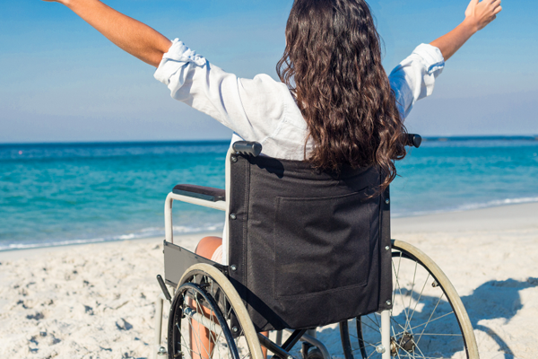 Person using a wheelchair enjoying the beach, symbolizing independence, inclusion and resilience during Disability Pride Month.