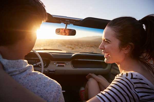 Couple from behind in convertible during sunset