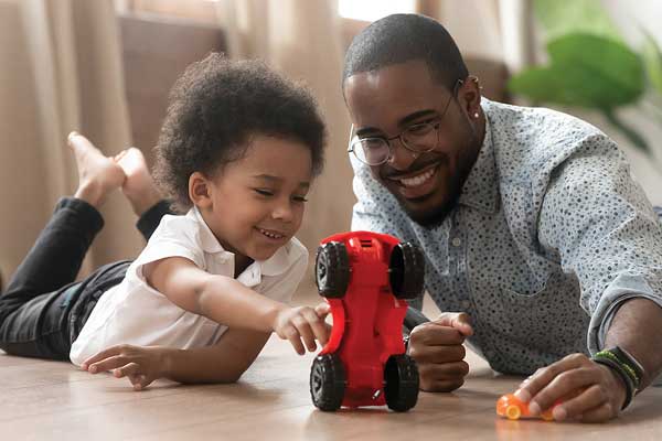 African American father and young son playing with red toy truck