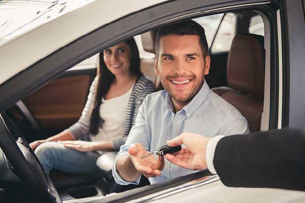 Couple in new car being handed the keys