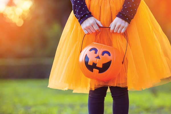 Girl trick-or-treater from waist down with pumpkin container