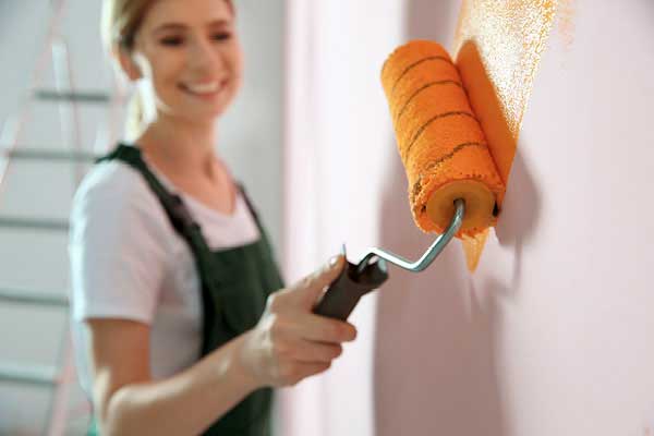 Woman painting interior with roller