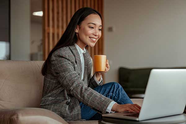 Asian woman on video conference call with cup of coffee