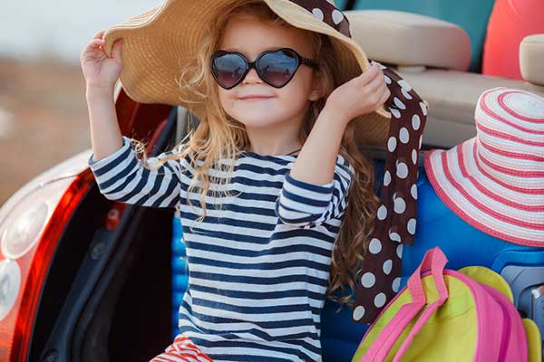 Girl with hat and heart sunglasses in the back of an SUV