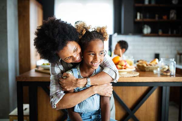 African American mother hugging her daughter in the kitchen