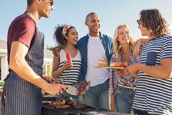 Group of friends helping themselves to food from the grill