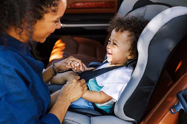 Hispanic mother and baby in car seat