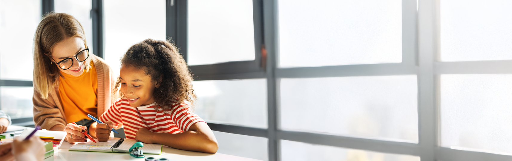Teacher helping student in classroom.