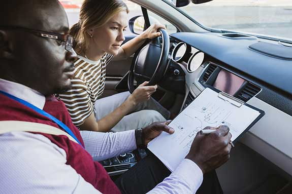 African American student driving teacher with student in car