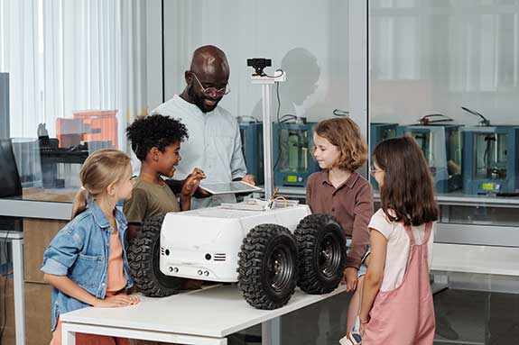 African American teacher with a number of diverse students in a robotics lab