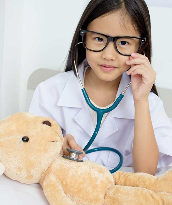 Little Asian girl playing doctor with teddy