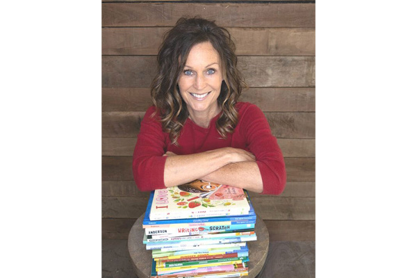 Shannon Anderson smiling behind a stack of children’s books.