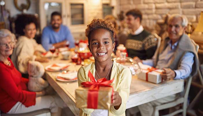 African American family celebrating a birthday with young boy holding a gift
