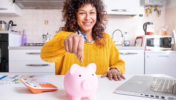 Smiling African American woman saving with piggy bank