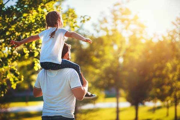 Dad from behind with daughter on shoulders