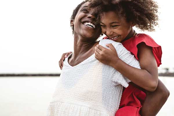 African American mom with young daughter piggy back riding