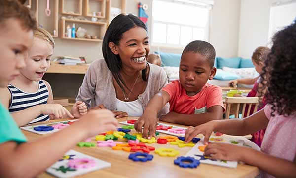 Hispanic teacher with student at table with gears